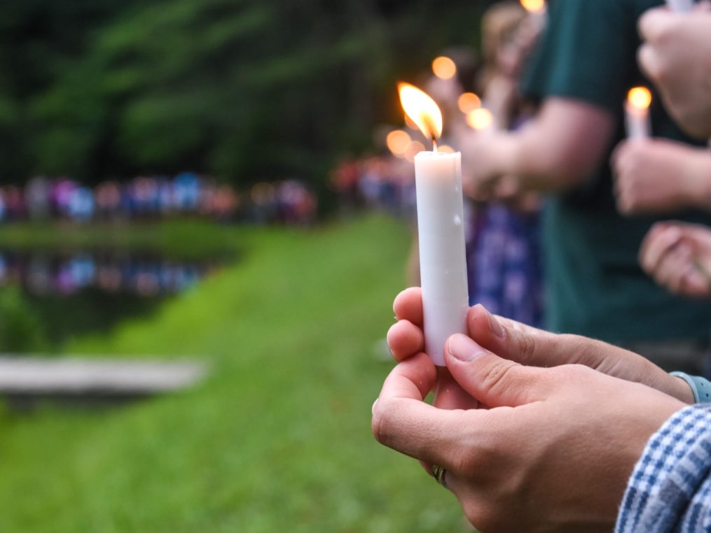 Campers holding candles at a ceremony
