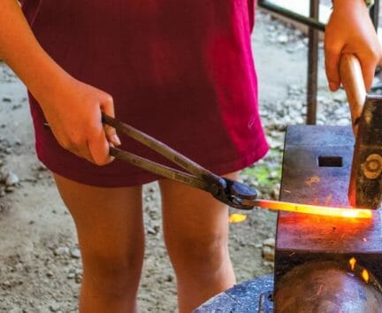 Camper at blacksmithing activity