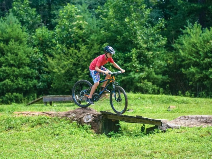 Camper biking over obstacle at the Hendersonville Adventure Day Camp