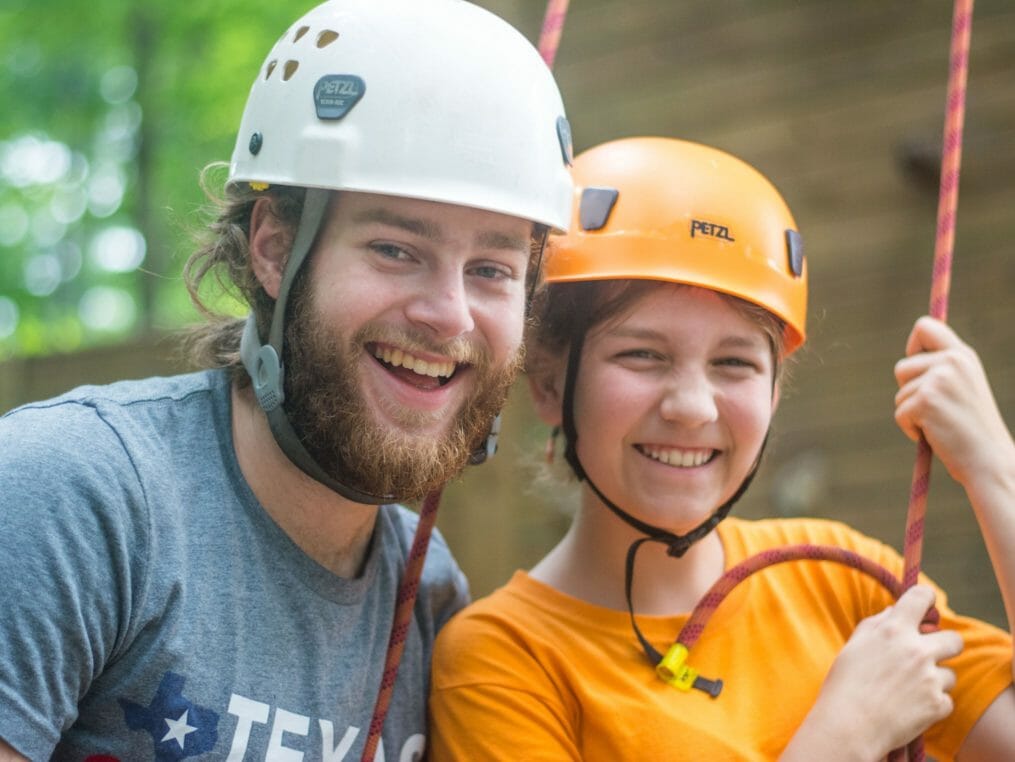 Camper and staff wearing yellow climbing helmets
